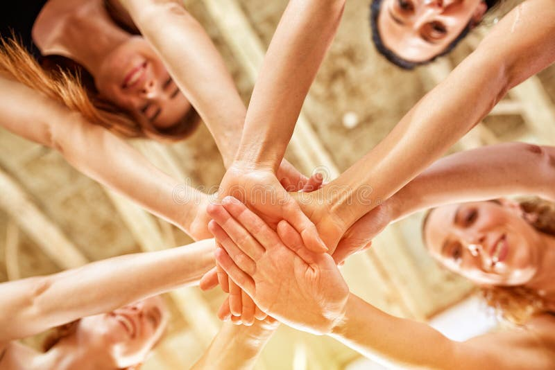 A group of people stacking their hands together in a gesture of teamwork and fitness motivation