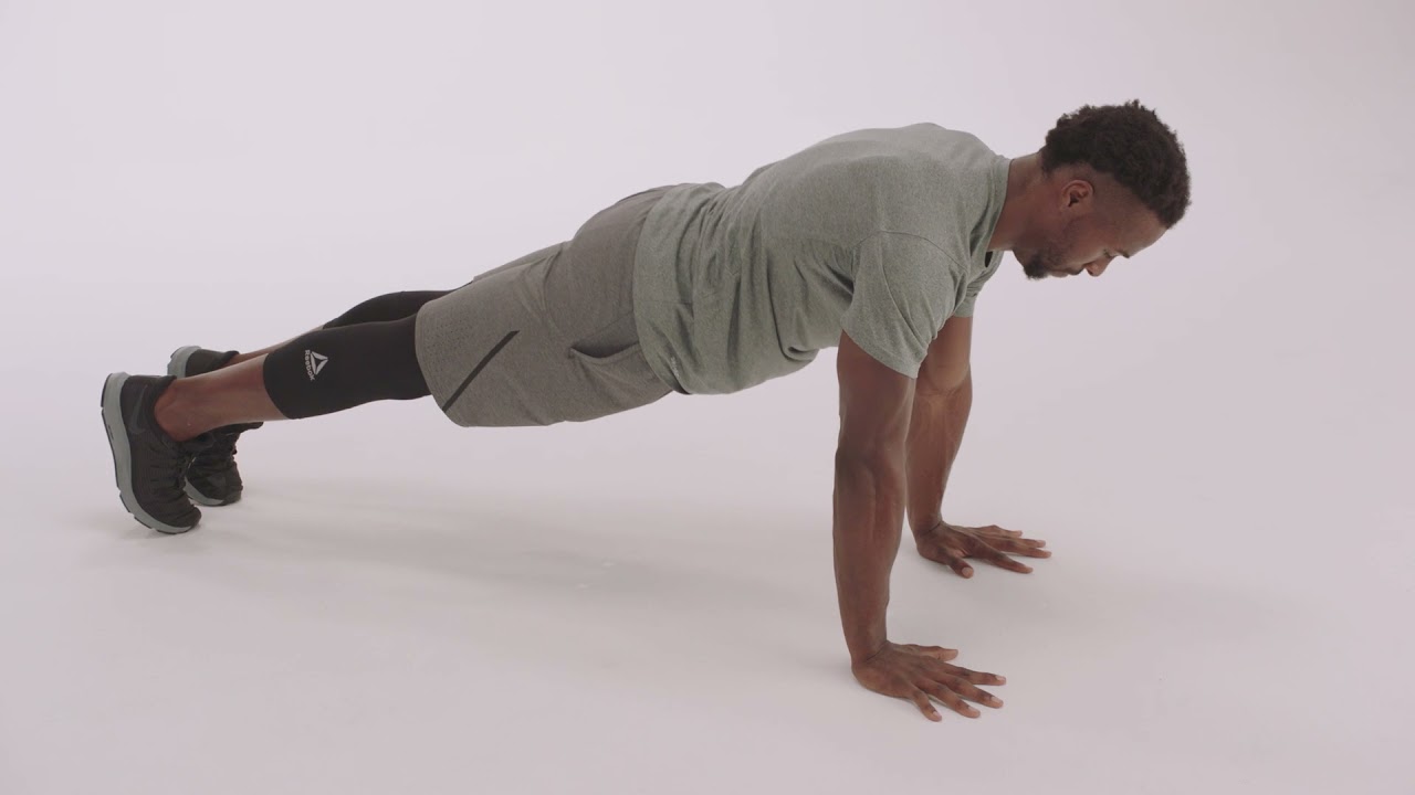 Man demonstrating proper push-up form and technique in a plain, well-lit environment